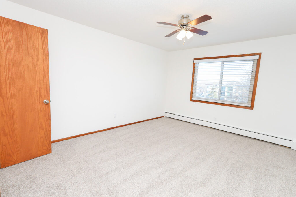 unfurnished bedroom with large window, carpet and ceiling fan