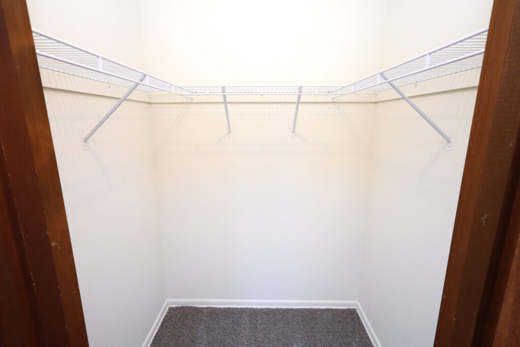 spacious walk-in closet with white shelf