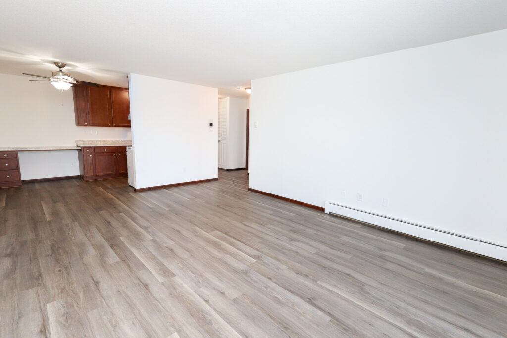 unfurnished living area with wood-style vinyl flooring kitchen with brown cabinets